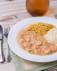 Shrimp strogonoff with rice and straw potato over wooden table