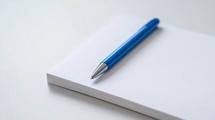Naklejka premium Minimalist White Notepad with Blue Pen on Clean White Background