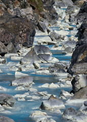 Small blue river water flow against a rocky backdrop.