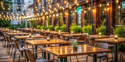 Outdoor restaurant seating area with empty tables and chairs adorned with wooden bars and twinkling electric light bulbs