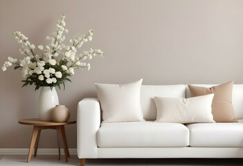 A white sofa with decorative pillows in a minimalist living room setting, with a vase of white flowers on a wooden side table.