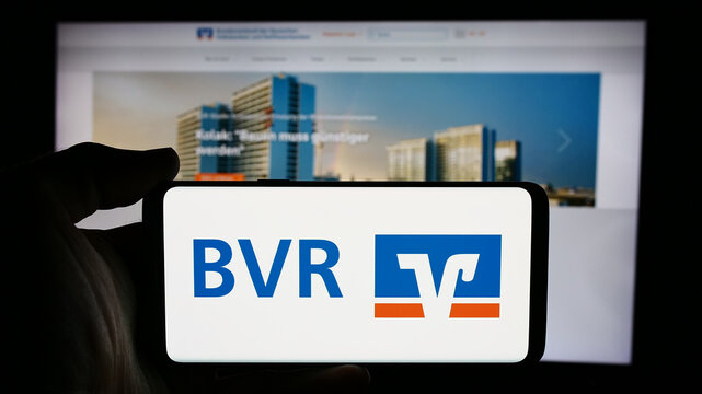Stuttgart, Germany - 08-19-2024: Person holding cellphone with logo of the National Association of German Cooperative Banks (BVR) in front of webpage. Focus on phone display.