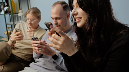 Happy friends enjoying time together playing with their phones in cozy setting