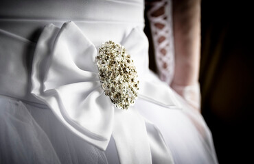 A fragment of the bride's wedding dress with a large white bow and a brooch with precious stones....