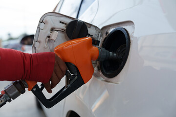 Fototapeta premium Close-up of gas station attendant's hand with orange fuel nozzle