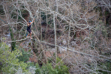 A tightrope walker walks along a cable stretched over a canyon.