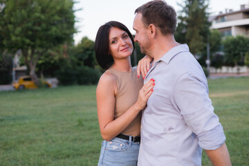 Obraz premium A happy smiling couple walking, hugging and kissing in park on late summer sunset