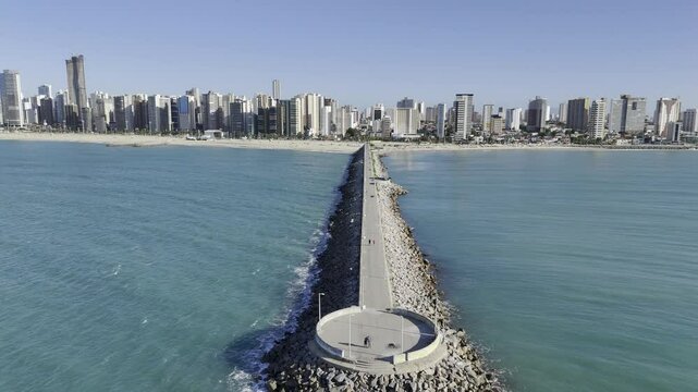 Drone flies up and away from Joao Cordeiro Pier at Praia de Iracema beach in Fortaleza, Ceara, Brazil
