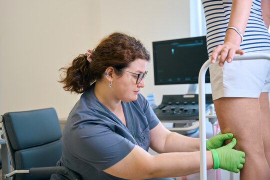 Female phlebologist examines the legs of a patient