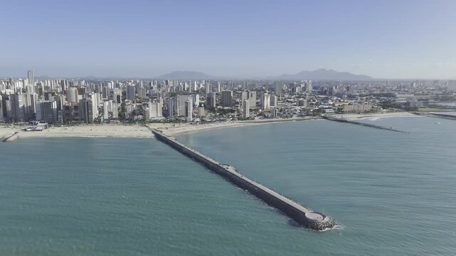 Drone orbits to left over ocean above Jo&atilde;o Cordeiro Pier at Praia de Iracema in Fortaleza, Ceara, Brazil
