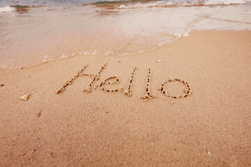 the inscription hello  on the seashore with palm trees