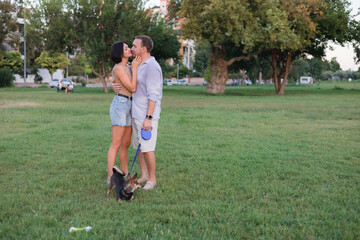 A happy smiling couple walking, hugging and kissing in park on late summer sunset