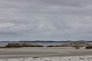 Isolated beach on an overcast day with rocks in the foreground. Near McMicking Inlet, Central...