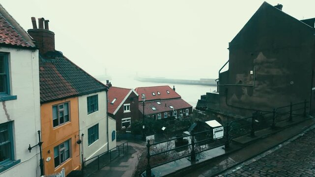 People walking along the quite streets of Whitby a sleepy fishing village on the Yorkshire coast of England. With cobbled streets and old stone built houses. Harbor walls and friendly public houses.