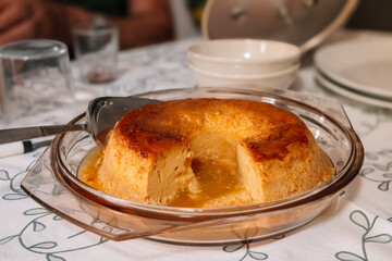 Flan cut into pieces in a bowl with a spatula to divide the portions.