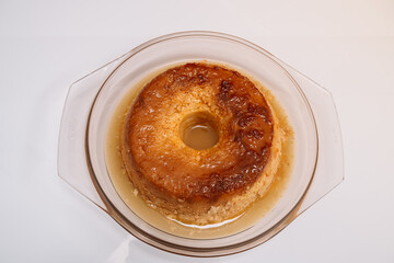 A dessert in a glass bowl with a yellow glaze. The dessert is a cake with a hole in the middle
