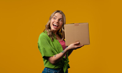 Excited smiling woman, online shopping consumer received cardboard order parcel box, desired purchase. Home courier delivery service. Sale, discounts
