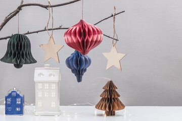 Eco-friendly sustainable Christmas interior decoration. Scandinavian Christmas paper honeycomb on a dry branch, wooden ornaments and lantern houses.