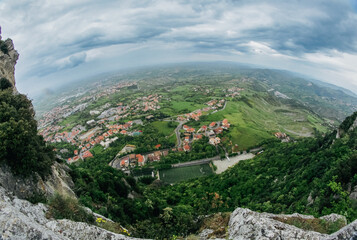 Fototapeta premium Aerial view of San Marino’s lush landscape and historical architecture on a cloudy day
