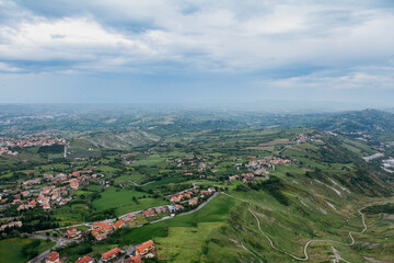 Obraz premium Vast green hills and valleys of San Marino under a cloudy sky