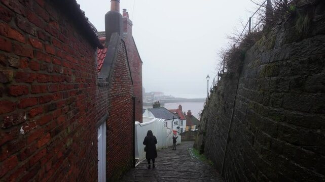 People walking along the quite streets of Whitby a sleepy fishing village on the Yorkshire coast of England. With cobbled streets and old stone built houses. Harbor walls and friendly public houses.