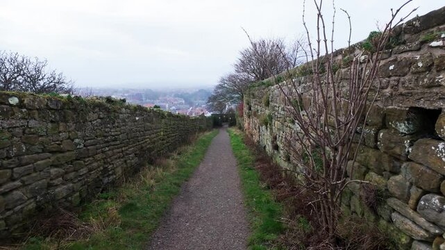 People walking along the quite streets of Whitby a sleepy fishing village on the Yorkshire coast of England. With cobbled streets and old stone built houses. Harbor walls and friendly public houses.