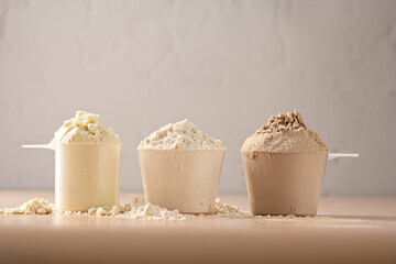 Protein powder in scoops. Different flavours of whey protein powder, copy space.