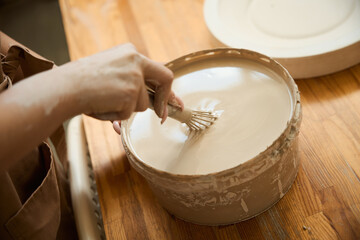 Lady in apron working with earthenware materials in pottery workshop