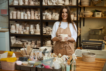 Smiling young woman holding a finished clay product