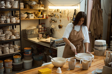 Pottery crafting. Woman sculpting with clay at table