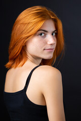 Fototapeta premium Cute red-haired girl, studio portrait on a black background.