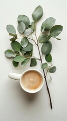 White mug and green leaves bouquet on plain white background Aerial view