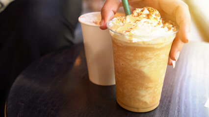 Detail of hand taking a pumpking spice latte, the perfect autumn beverage