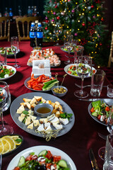 Set of dorblu cheese, parmesan, brie cheese, honey and walnuts, Greek salad of fresh cucumber, tomato, sweet pepper, lettuce, red onion, feta cheese and olives on table.