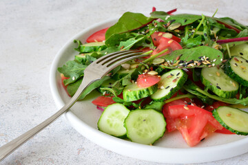 a plate of salad with vegetables and seeds with a fork close up   