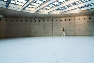 Woman walking in a large museum area with empty walls. Young woman walking in the empty gallery