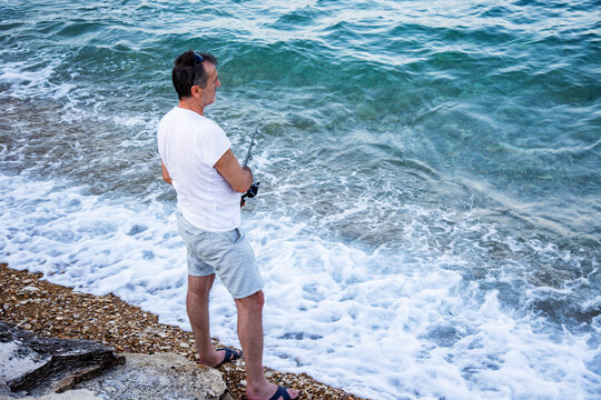 Man with fishing rod against blue sea, solitude by the sea