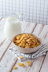 cornflakes in a bowl, milk in a carafe. a healthy breakfast.