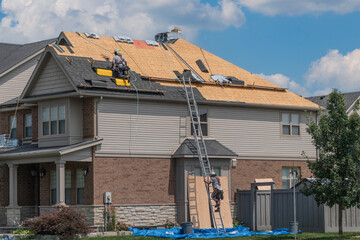 A roofer descends from a roof to get his tools