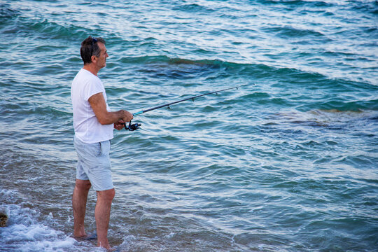 Focused fisherman by the ocean with fishing rod