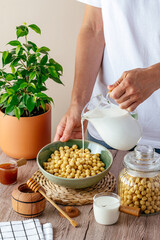The girl pours milk into a bowl with cornflakes