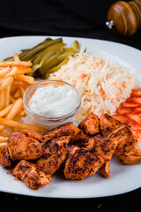 Fried chicken pieces with coleslaw, French fries, tomatoes, pickled cucumbers and sauce.
