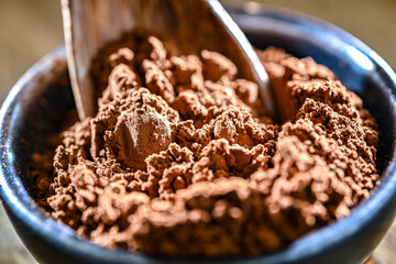Bowl of cocoa powder on wooden table