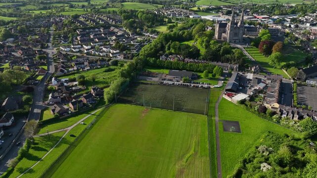 St. Patrick's Cathedral, County Armagh, Northern Ireland, May 2023. Drone slowly orbits clockwise with Sherries Field GAA football grounds in the foreground surrounded by the Armagh townscape.