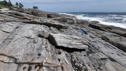 Living beside the Ocean along the rocky coastline in Maine as waves break on beach in summertime