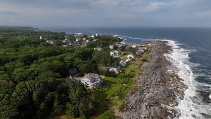 Fototapeta premium Living beside the Ocean along the rocky coastline in Maine as waves break on beach in summertime