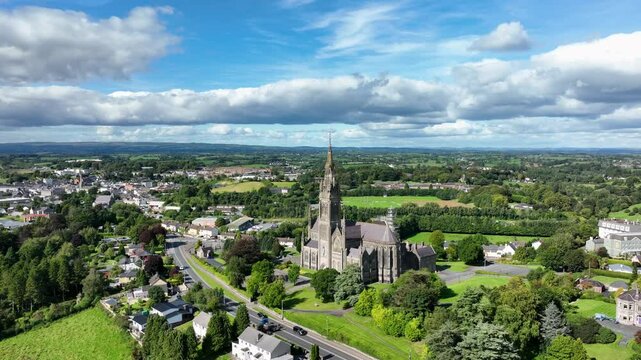 St. Macartan's Cathedral, County Monaghan, Ireland, September 2022. Drone orbits counter clockwise around the Roman Catholic church under a cloudy sky with Monaghan town in the background.