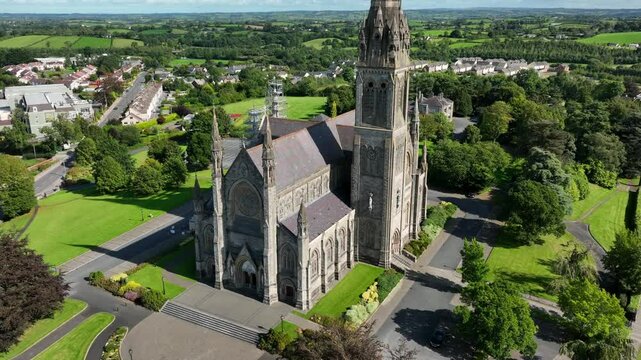 St. Macartan's Cathedral, County Monaghan, Ireland, September 2022. Drone ascends slowly pushing closer showcasing the Gothic Revival architecture from above with its spire bathed in warm sunlight.