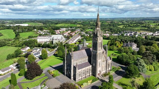 St. Macartan's Cathedral, County Monaghan, Ireland, September 2022. Drone orbits counter clockwise around the Gothic Revival church bathed in sunlight revealing Monaghan town in the distance.