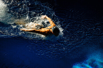 Female athlete swims with a butterfly style. Splashes of water scatter in different directions